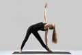 Young attractive woman standing in Utthita Trikonasana pose, gre