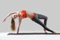 Young attractive woman stretching in Camatkarasana pose, grey st
