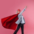 Young attractive woman superhero. Girl in a business suit and a mask with red cloak of hero. Royalty Free Stock Photo