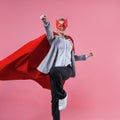 Young attractive woman superhero. Girl in a business suit and a mask with red cloak of hero. Royalty Free Stock Photo