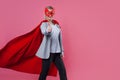 Young attractive woman superhero. Girl in a business suit and a mask with red cloak of hero. Royalty Free Stock Photo