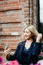 A young attractive woman takes a picture of herself on her smartphone, sitting on a street bench during the lunch break Royalty Free Stock Photo