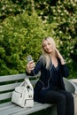 A young attractive woman takes a picture of herself on her smartphone, sitting on a street bench during the lunch break Royalty Free Stock Photo