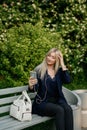 A young attractive woman takes a picture of herself on her smartphone, sitting on a street bench during the lunch break Royalty Free Stock Photo