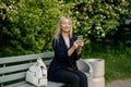 A young attractive woman takes a picture of herself on her smartphone, sitting on a street bench during the lunch break Royalty Free Stock Photo