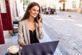 Young attractive woman talking on mobile phone and smiling while sitting alone in coffee shop during free time and working on Royalty Free Stock Photo