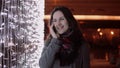 Young attractive woman talking on the phone in the falling snow at Christmas night standing near lights wall, Royalty Free Stock Photo