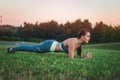 Young attractive woman training in the park. Exercise plank. Fit