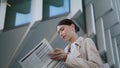 Woman turning newspaper pages standing outdoors close up. Businesswoman reading