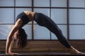 Young attractive woman in Urdhva Dhanurasana pose, studio evenin