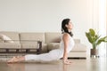 Young attractive woman in Urdhva mukha shvanasana pose, living r