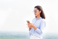 Young attractive woman uses smartphone on the background of mountains and trees. Summer and modern technologies Royalty Free Stock Photo