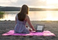 Young attractive woman using laptop on beach at sunset. Royalty Free Stock Photo