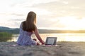 Young attractive woman using laptop on beach at sunset. Royalty Free Stock Photo