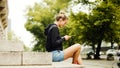 Young attractive woman using phone in city. Sitting and smileing. Royalty Free Stock Photo