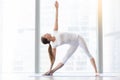 Young attractive woman in Utthita Trikonasana pose against floor