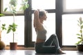 Young attractive woman in variation of Gomukasana pose, home int Royalty Free Stock Photo