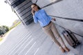 Beautiful business woman using mobile phone and pulling her suitcase. Caucasian female traveler with suitcase at airport Royalty Free Stock Photo