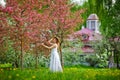 A young attractive woman walks through the spring blooming green park, enjoying nature. A healthy, smiling girl whirls in the Royalty Free Stock Photo