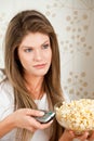 Young attractive woman wathcing TV and holding pop Royalty Free Stock Photo