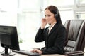 A young attractive woman wearing a black jacket in a black jacket is sitting at her desk in a executive chair. Holds a Royalty Free Stock Photo