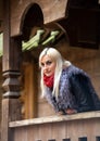 A young attractive woman wearing fur black jacket standing on background of wooden house. Royalty Free Stock Photo