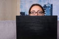 Young attractive woman wearing glasses peeking behind the laptop Royalty Free Stock Photo