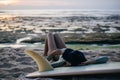 young attractive woman in wetsuit relaxing on surfboard on seashore