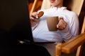 Young attractive business woman is working on the laptop at mountain resort with a cup of tea and cookie. Female relaxes Royalty Free Stock Photo