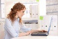 Young attractive woman working on laptop in office Royalty Free Stock Photo