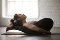 Young attractive woman in Yogic Sleep pose, white loft studio