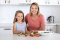 Young attractive woman cooking together with her sweet beautiful blond little 6 or 7 years old daughter smiling happy preparing sa