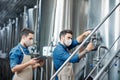 Young attractive workers in aprons and protective masks close vent on kettle Royalty Free Stock Photo