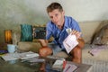 Young attractive worried and stressed man at home calculating month tax expenses with calculator accounting payments doing bank pa Royalty Free Stock Photo