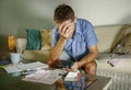 Young attractive worried and stressed man at home calculating month tax expenses with calculator accounting payments doing bank pa Royalty Free Stock Photo