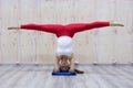 Young attractive yogi woman practicing yoga concept, standing in variation of Pincha Mayurasana exercise, handstand pose, working Royalty Free Stock Photo