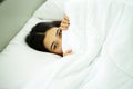 Young attrative Asian woman on white pillow and bed sheet in bedroom relaxing on holiday Royalty Free Stock Photo