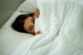 Young attrative Asian woman on white pillow and bed sheet in bedroom relaxing on holiday Royalty Free Stock Photo