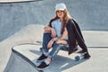 Young attrctive girl is sitting on her longboard at skatepark