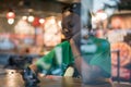 Young authentic black woman sitting with phone in city coffee shop at night