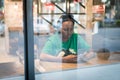 Young authentic black woman sitting with phone in city coffee shop at night