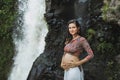 Young authentic pregnant woman near amazing waterfall. Harmony with nature