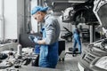 Auto mechanic in overalls working changing old spark plugs Royalty Free Stock Photo