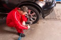 Young auto mechanic checking the air pressure of a tyre Royalty Free Stock Photo