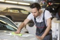 Young automobile mechanic cleaning car in repair shop