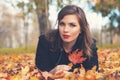 Young autumn woman lying on fall leaves outdoors