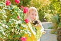 Young autumnal girl hug a cat behind beautiful flowers. Charming woman wearing warm yellow sweater is resting with a cat Royalty Free Stock Photo