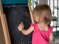 Young baby girl cleaning a blackboard Royalty Free Stock Photo