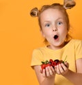 Young baby girl kid hold berries fruits in hands surprised happy laughing screaming on yellow Royalty Free Stock Photo