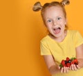 Young baby girl kid hold berries fruits in hands surprised happy laughing screaming on yellow Royalty Free Stock Photo